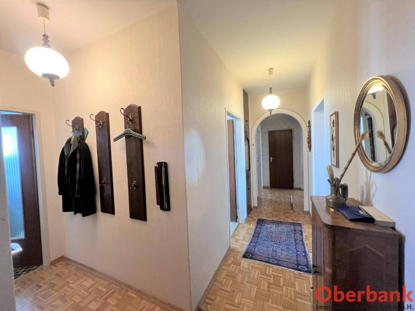 Eingangsbereich mit Parkettboden, Garderobe und einem Spiegel, der den Raum optisch erweitert.