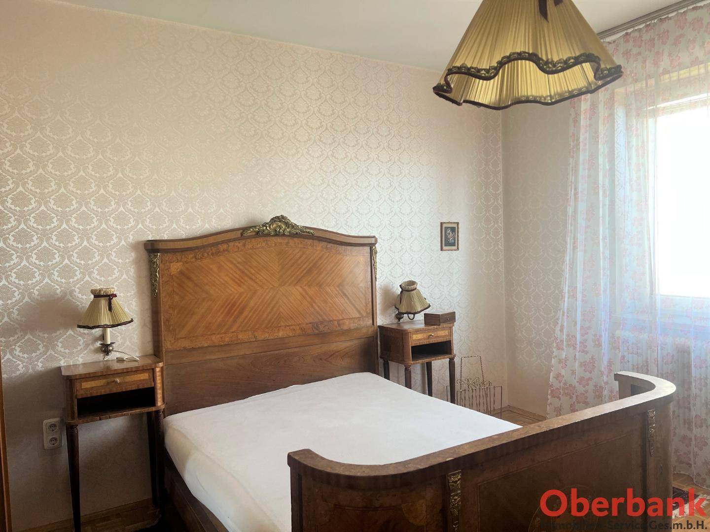 Schlafzimmer mit antikem Holzdoppelbett, passenden Nachttischen und gemusterter Tapete.