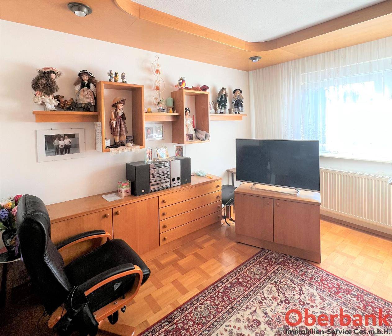 Wohnzimmer mit Holzboden, Teppich, TV-Möbeln und dekorativen Elementen.