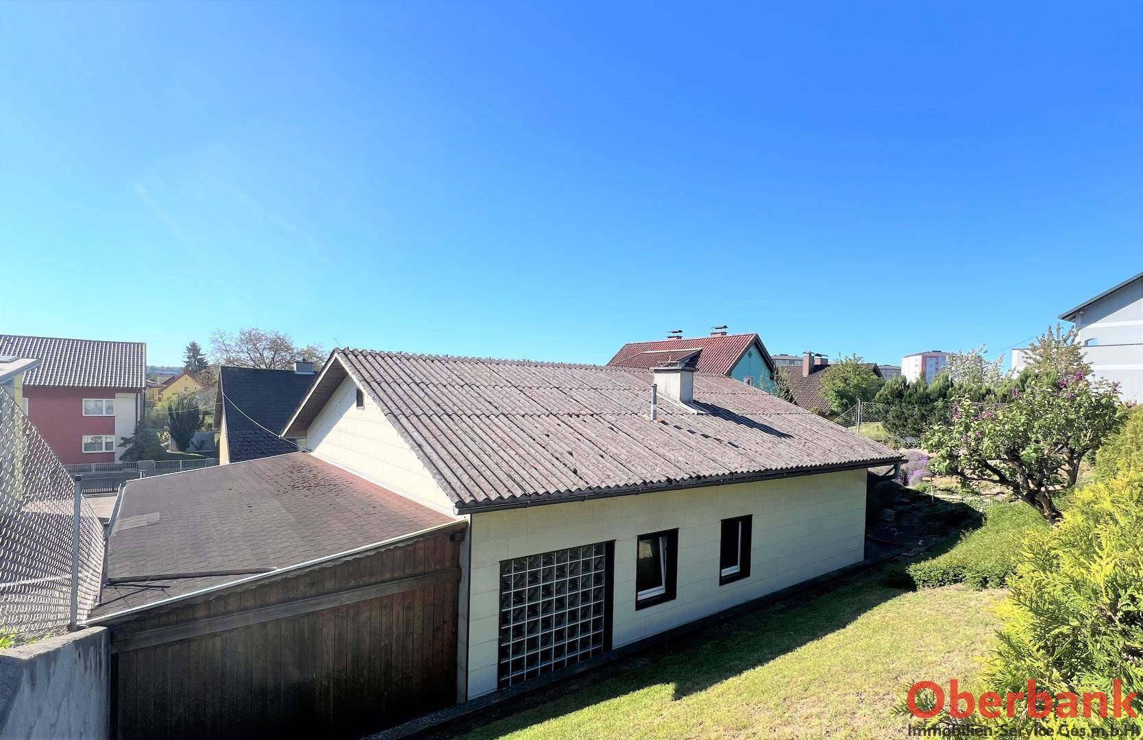 Ansicht eines Nebengebäudes mit Garage und einem Wellblechdach im Grünen.