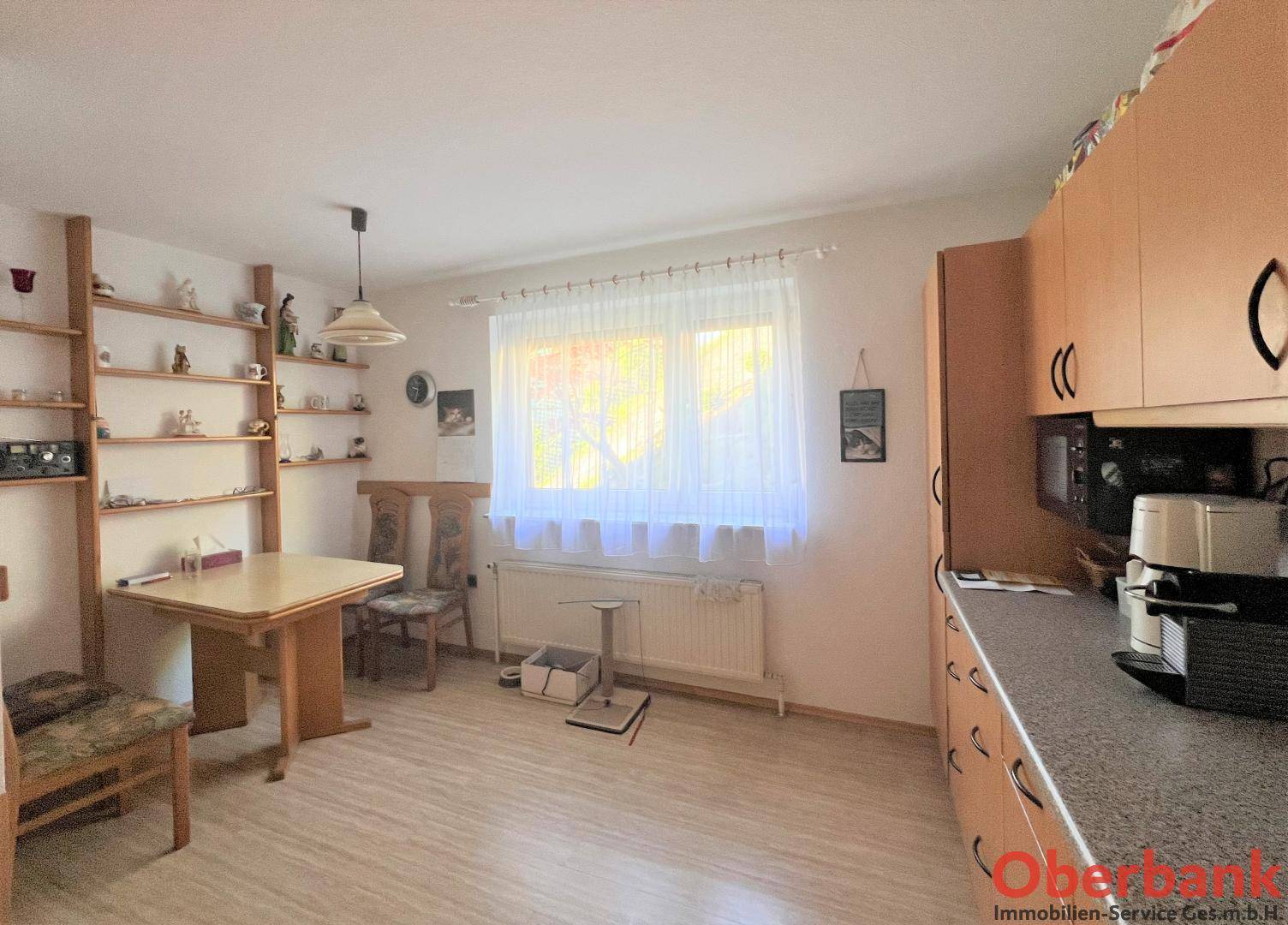 Helle Küche mit Essbereich, Holzschränken, Laminatboden und einem Fenster.