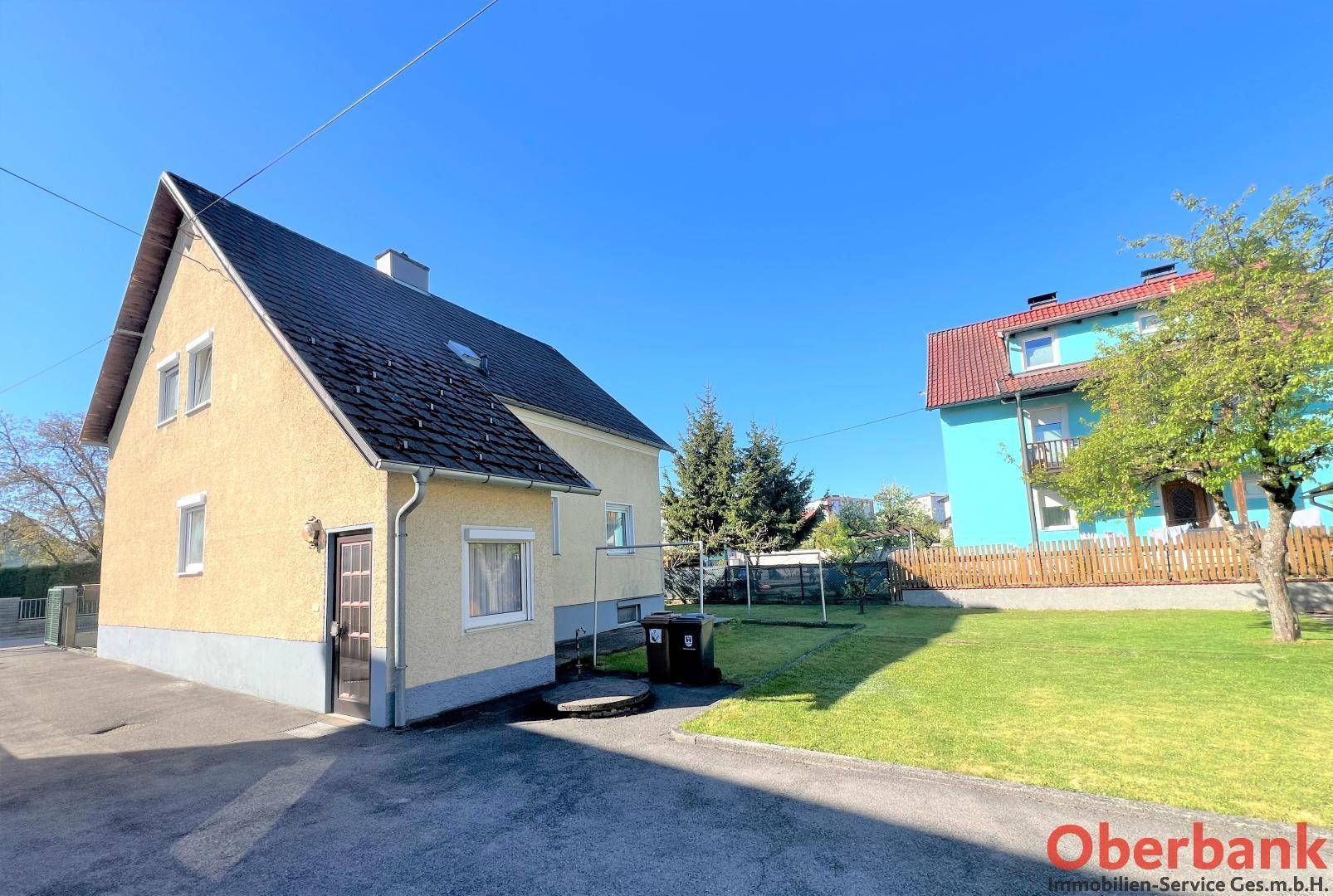 Seitenansicht des Hauses mit Gartenbereich, Zufahrt und angrenzendem Nachbargebäude.