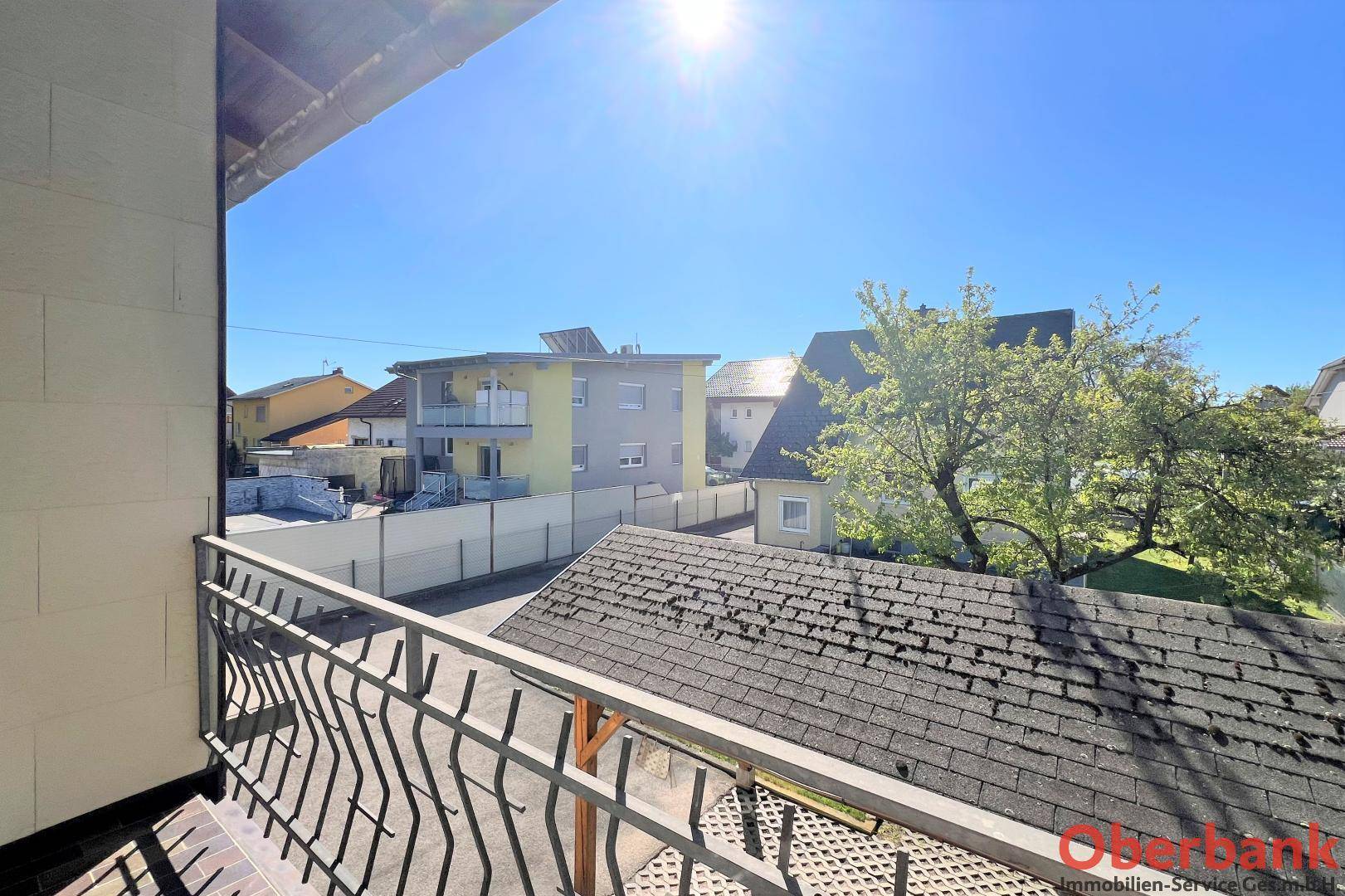 Sonniger Ausblick von einem Balkon auf die umliegenden Dächer und Nachbarhäuser.