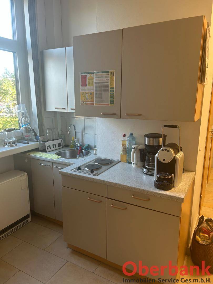 Kleine Küchenzeile mit Spüle, Kochplatten und Kaffeemaschine, ideal für Pausen.