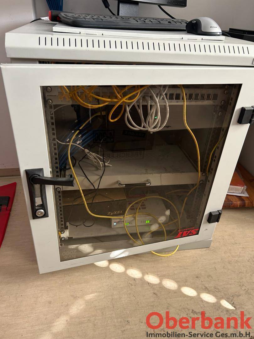 Technischer Raum mit einem Serverschrank voller Kabel und Netzwerkgeräten für die Infrastruktur.