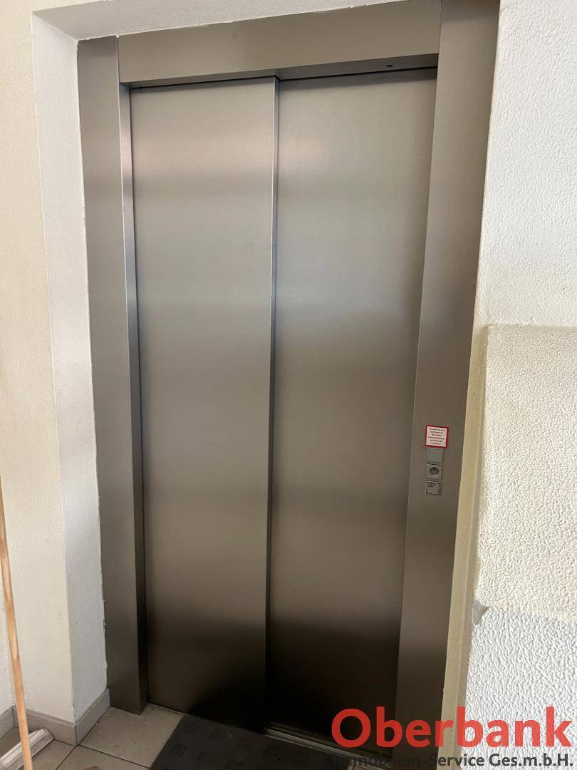 Moderner Aufzug mit Edelstahltüren in einem Flur, bereit zur Nutzung in diesem Gebäude.