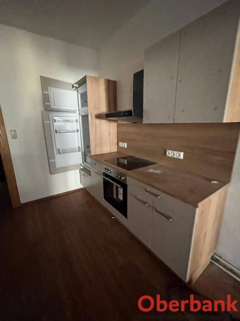 Moderne Küchenzeile mit Holzarbeitsplatte, integrierten Geräten und Dunstabzugshaube.