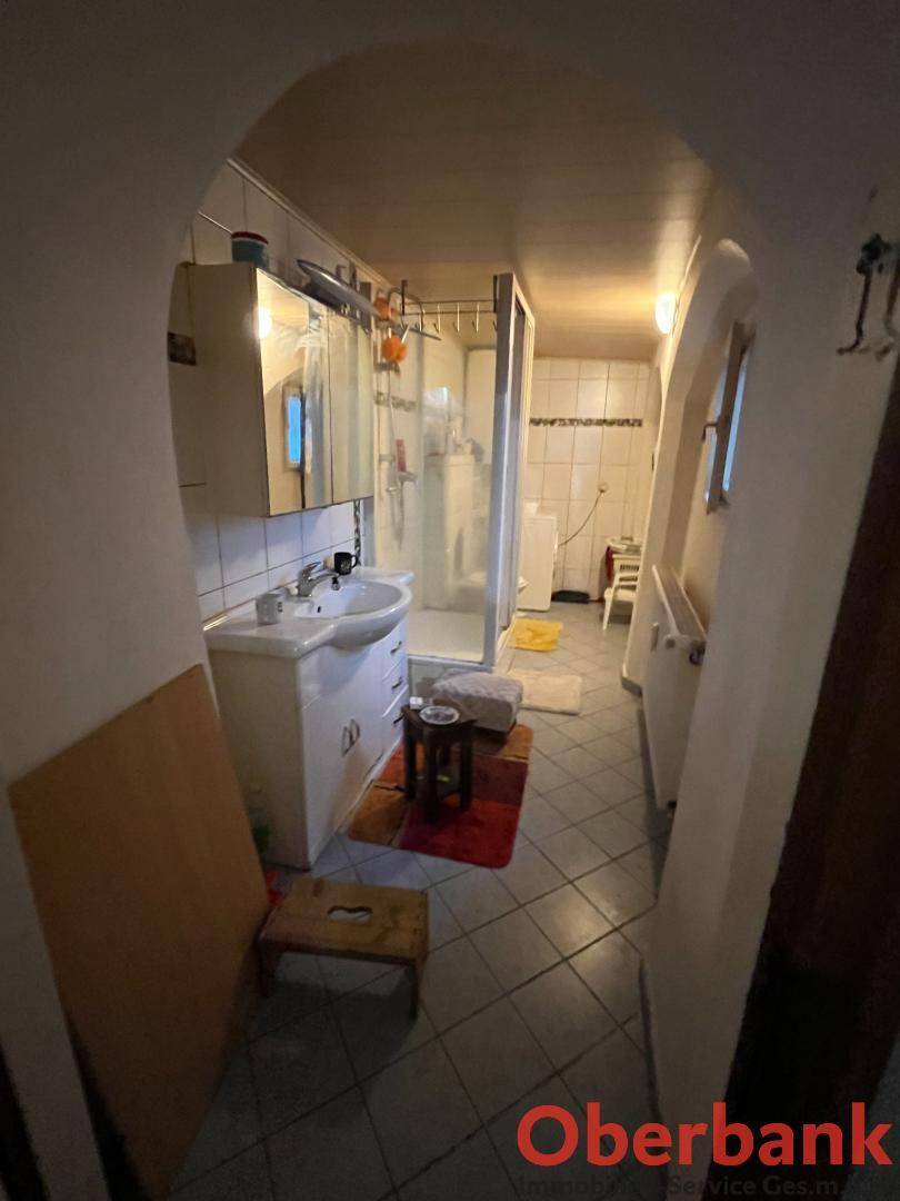 Badezimmer mit Fliesenboden, Duschkabine, Waschbecken und Spiegelschrank.