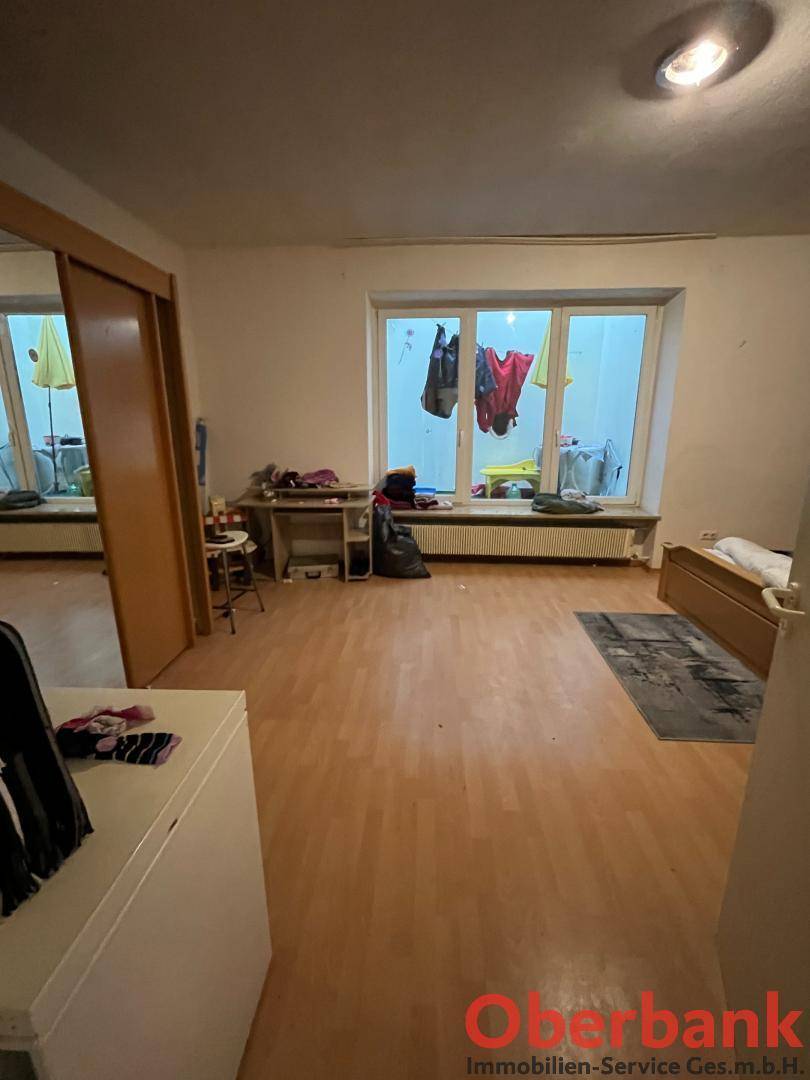 Heller Raum mit Laminatboden und einem großen Fenster, das viel Tageslicht hereinlässt.
