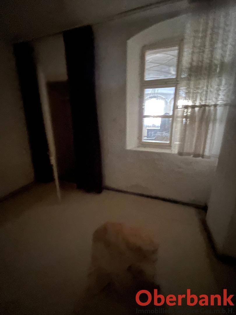 Innenraum mit einem Fenster, das natürliches Licht hereinlässt, und einem Blick auf einen anderen Raum.
