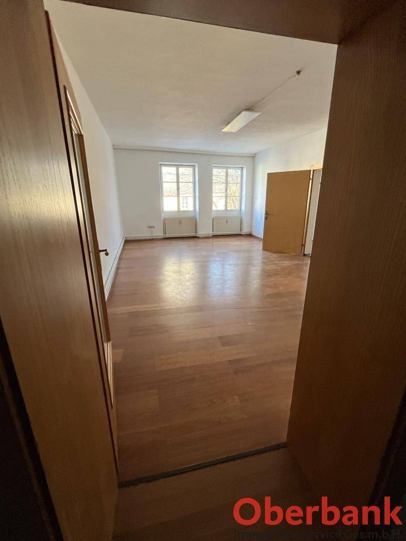Leerer Raum mit Holzplankenboden und zwei Fenstern, bereit für die individuelle Einrichtung.