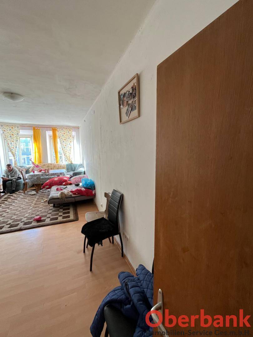 Helles Wohnzimmer mit Laminatboden, Teppich und einem großen Fenster, das viel Licht spendet.