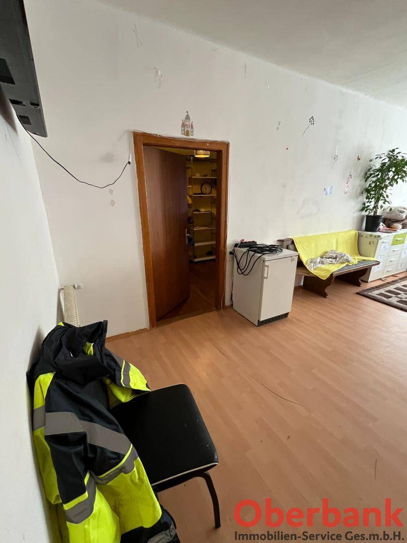 Wohnraum mit Laminatboden und einer Tür, die zu einem praktischen Abstellraum führt.