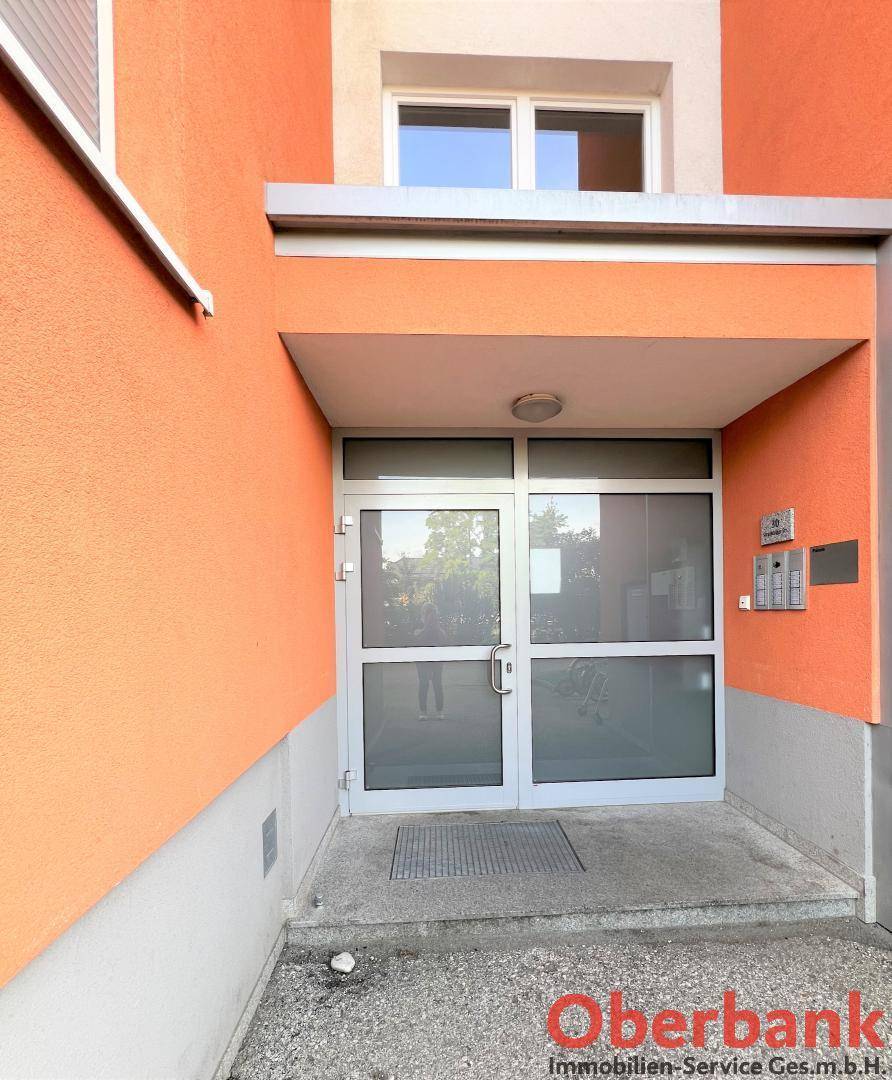 Eingangsbereich des Mehrfamilienhauses mit Glastüren und orangefarbener Fassade.