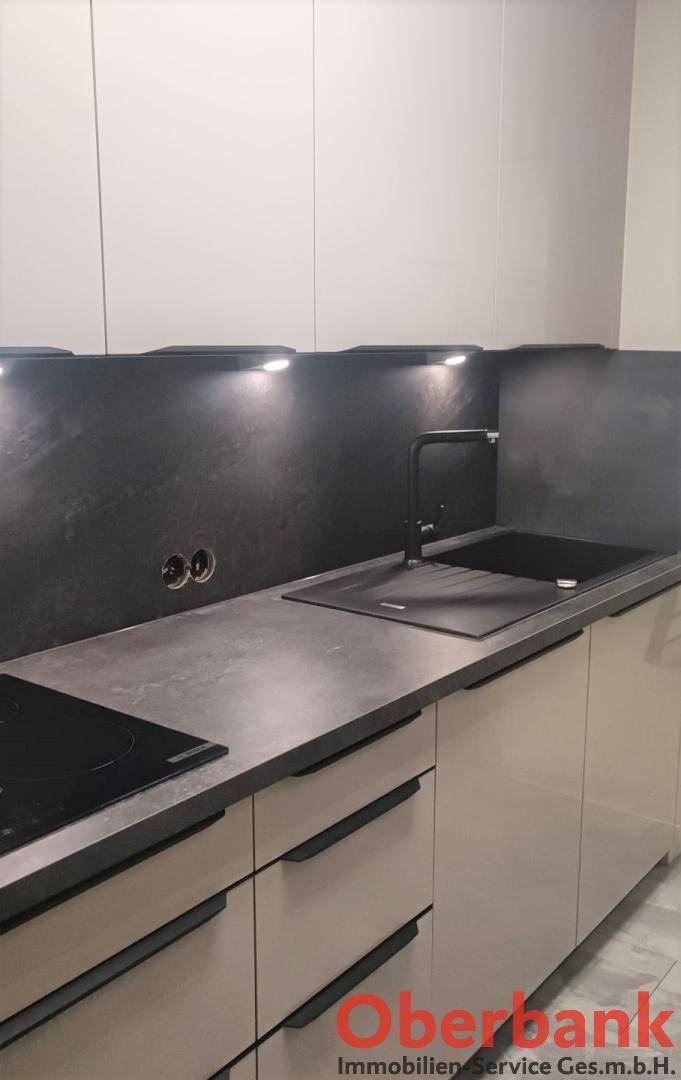 Nahaufnahme der Küchenarbeitsplatte mit schwarzer Spüle und modernem Wasserhahn.