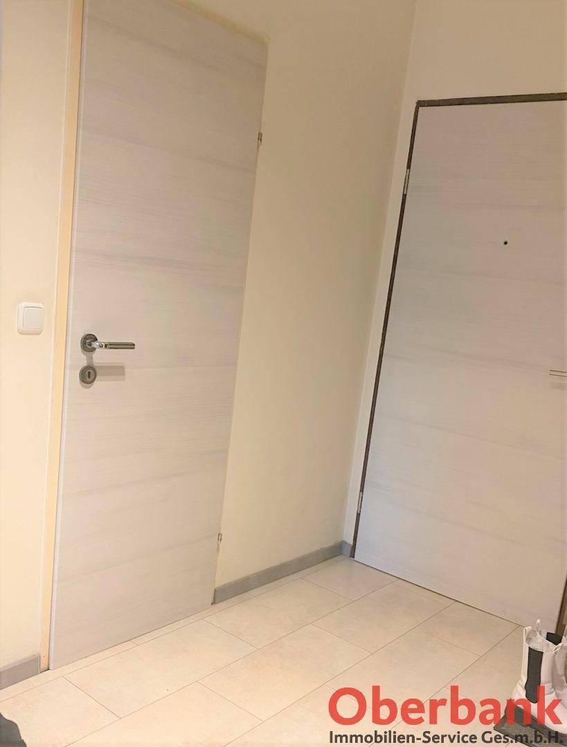 Heller Flur mit zwei modernen Holztüren und Fliesenboden, einladend gestaltet.