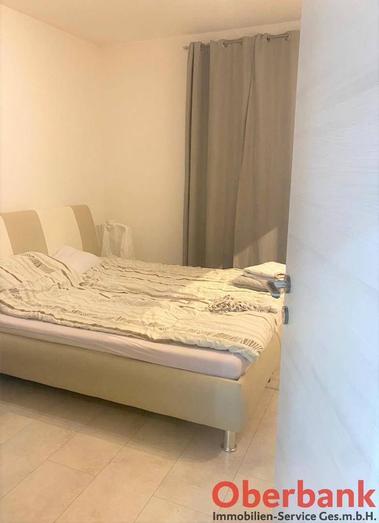 Schlafzimmer mit Doppelbett und beigen Vorhängen, bietet eine ruhige Atmosphäre.