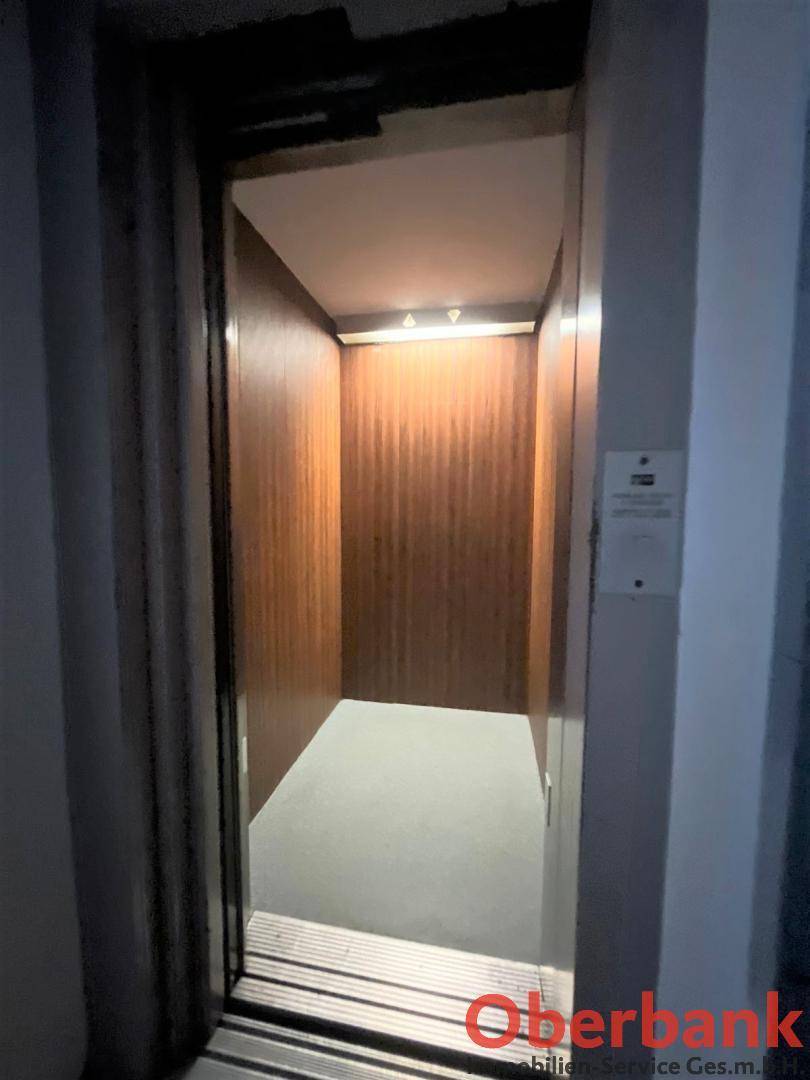 Innenansicht eines Aufzugs mit Holzverkleidung, sauber und gut beleuchtet.