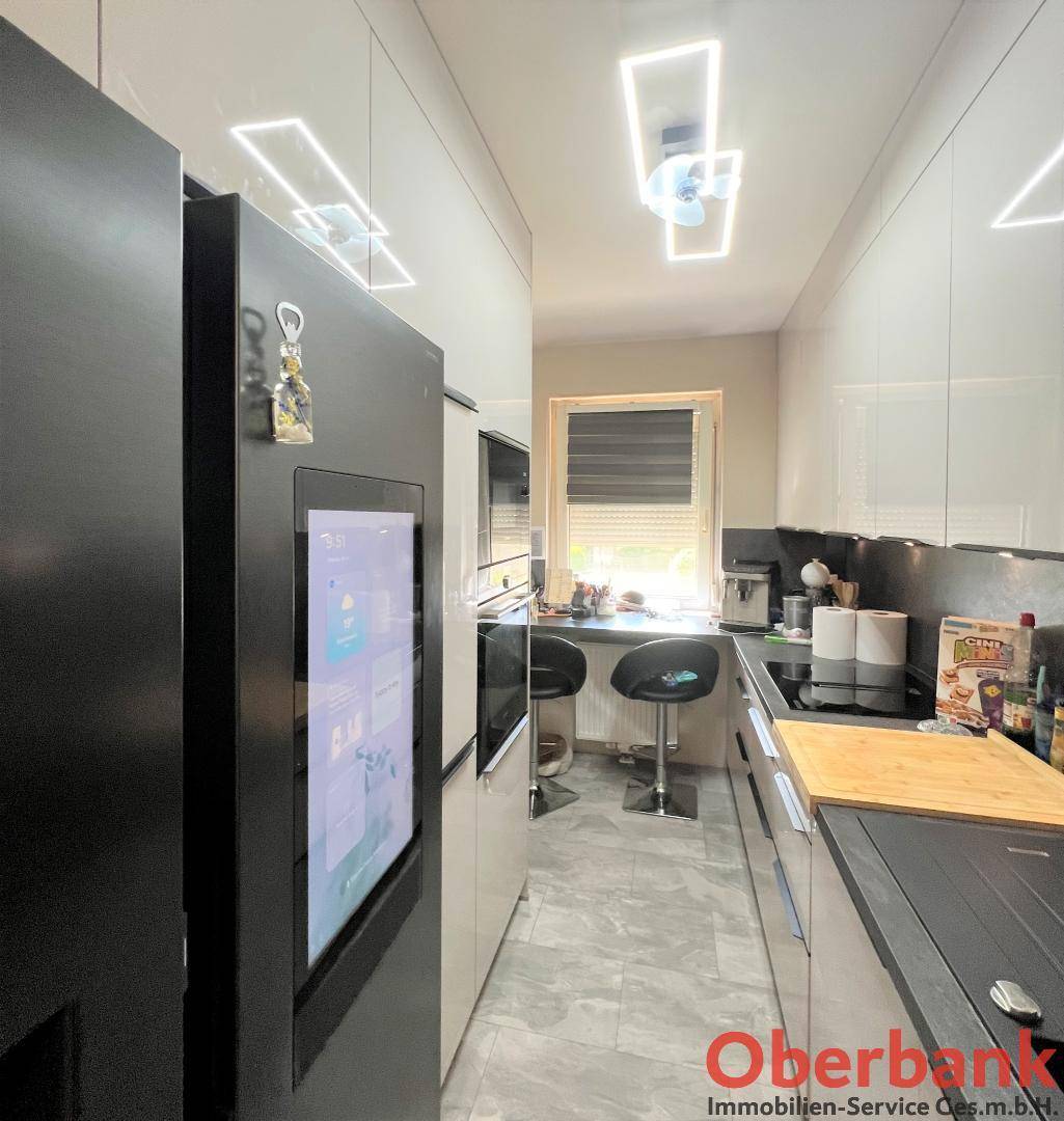Moderne Küche mit Smart-Kühlschrank, Induktionskochfeld und integrierter Spüle, hell beleuchtet.