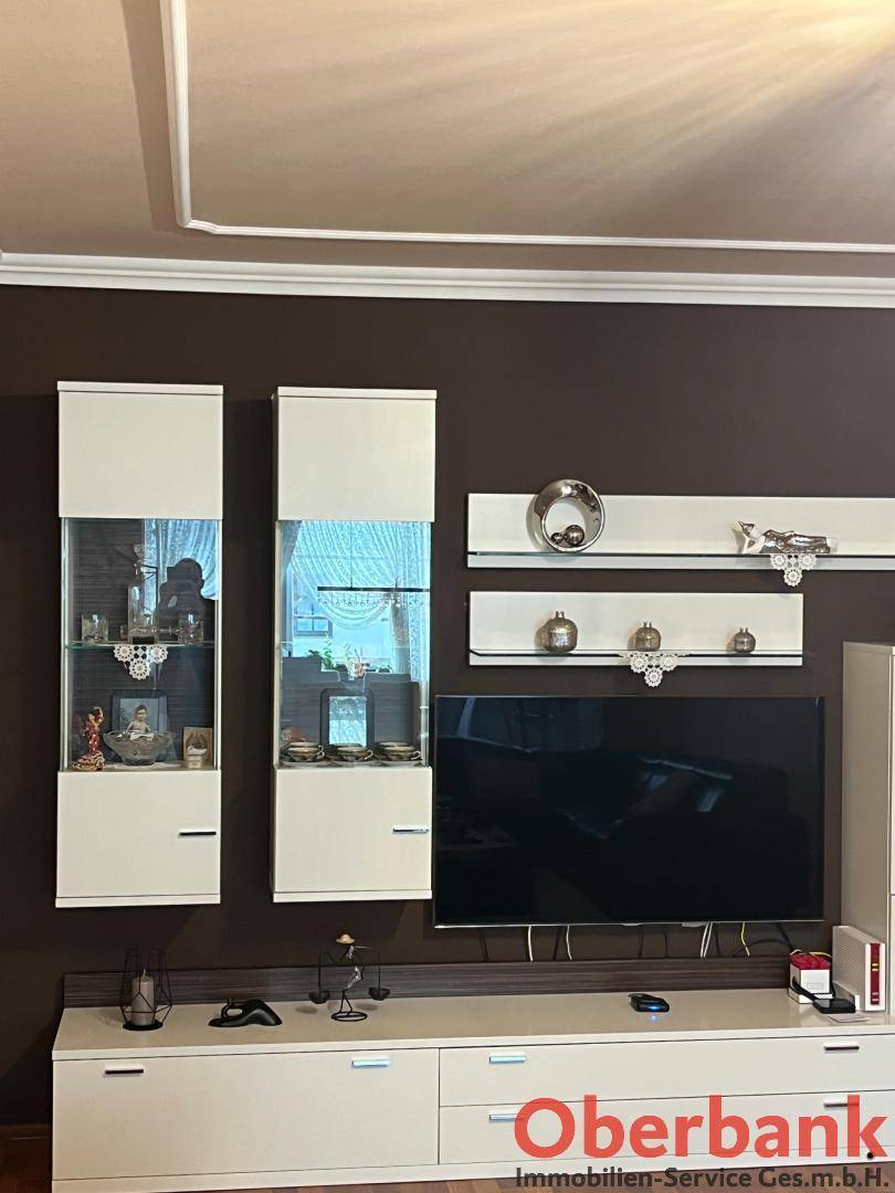 Moderner Wohnbereich mit TV-Möbeln, Vitrinen und dunkler Akzentwand.
