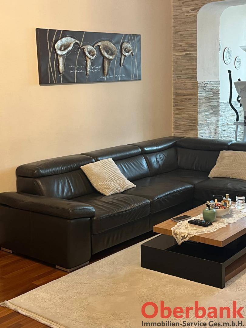 Geräumiges Wohnzimmer mit großem Ledersofa, Couchtisch und dekorativer Wandkunst.