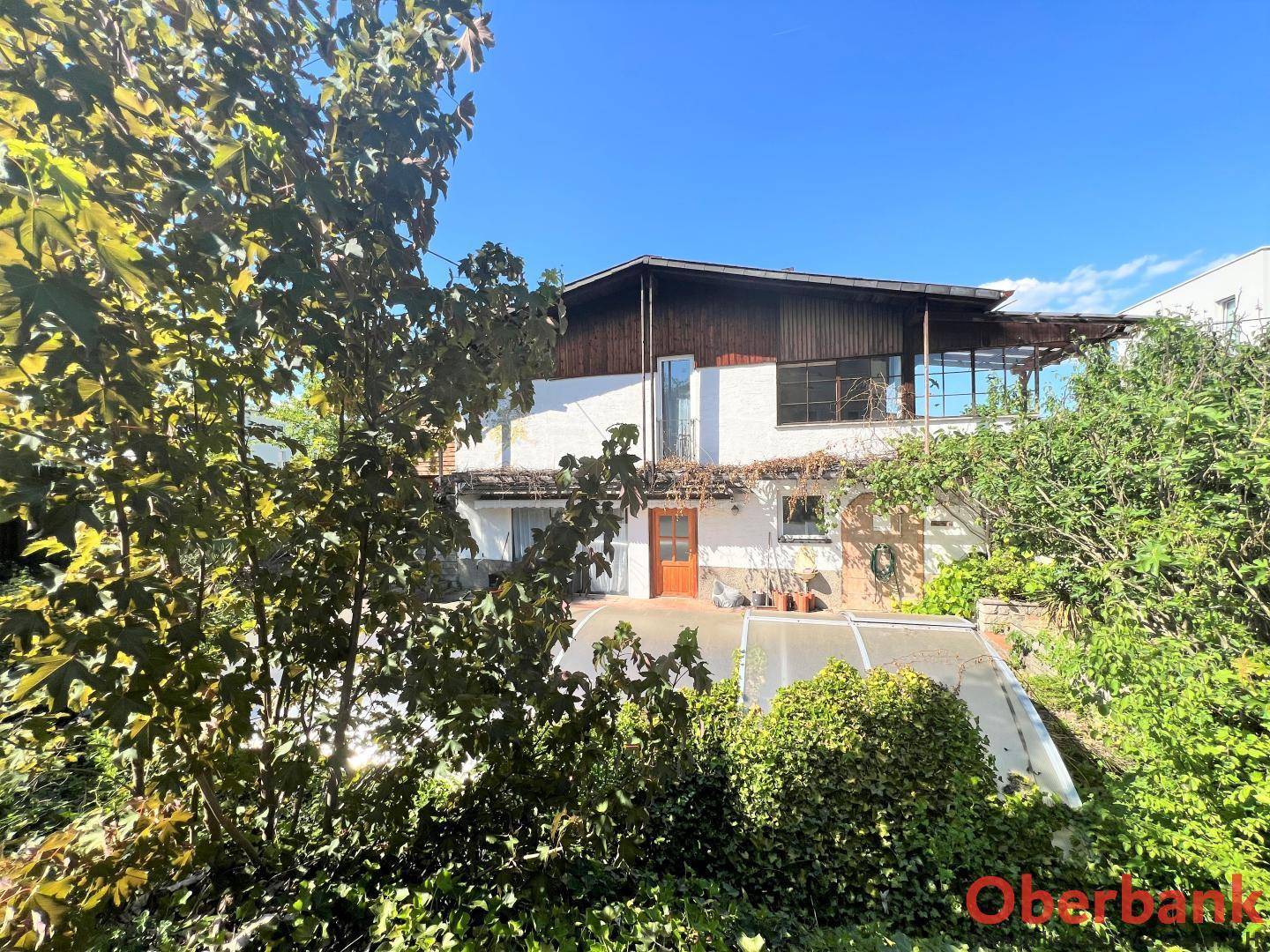 Rückansicht des Hauses mit einer großen Terrasse und üppiger Vegetation im Vordergrund.