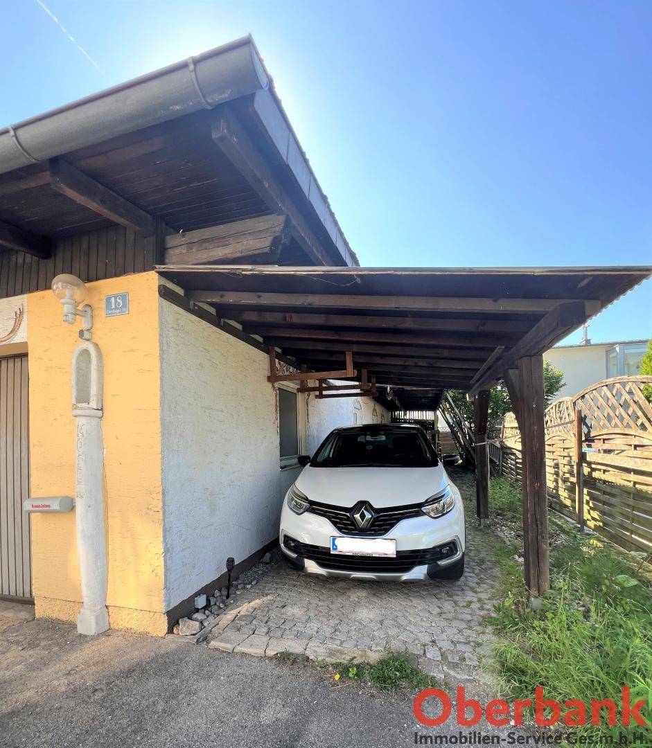 Überdachter Stellplatz für ein Fahrzeug unter einem Carport neben dem Haus.