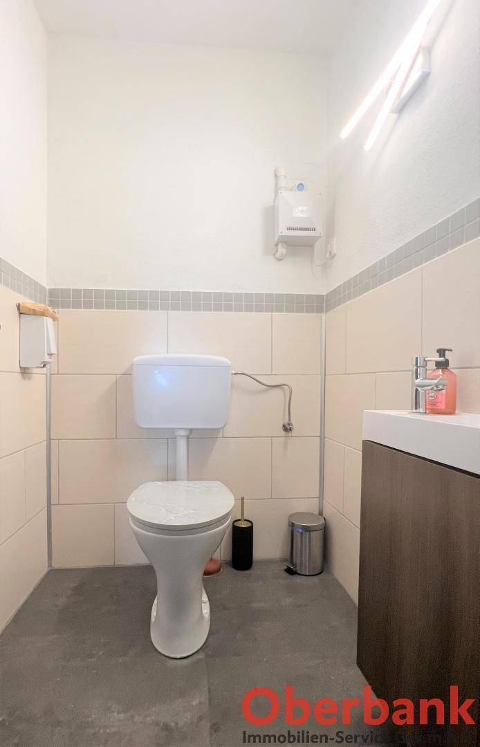 Kleines Gäste-WC mit modernem Waschbecken und Wandfliesen in neutralen Farben.