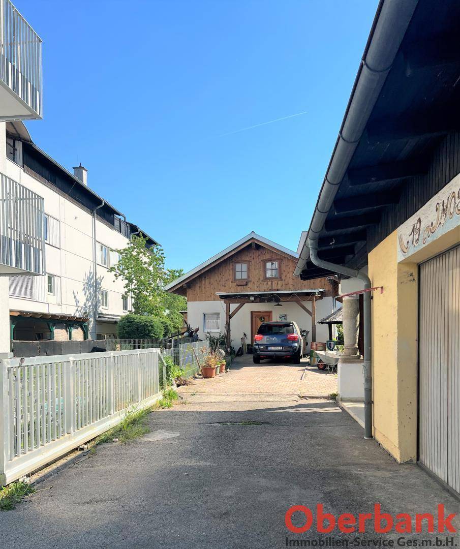 Zufahrt zwischen Gebäuden, die zum hinteren Bereich des Hauses mit Carport führt.