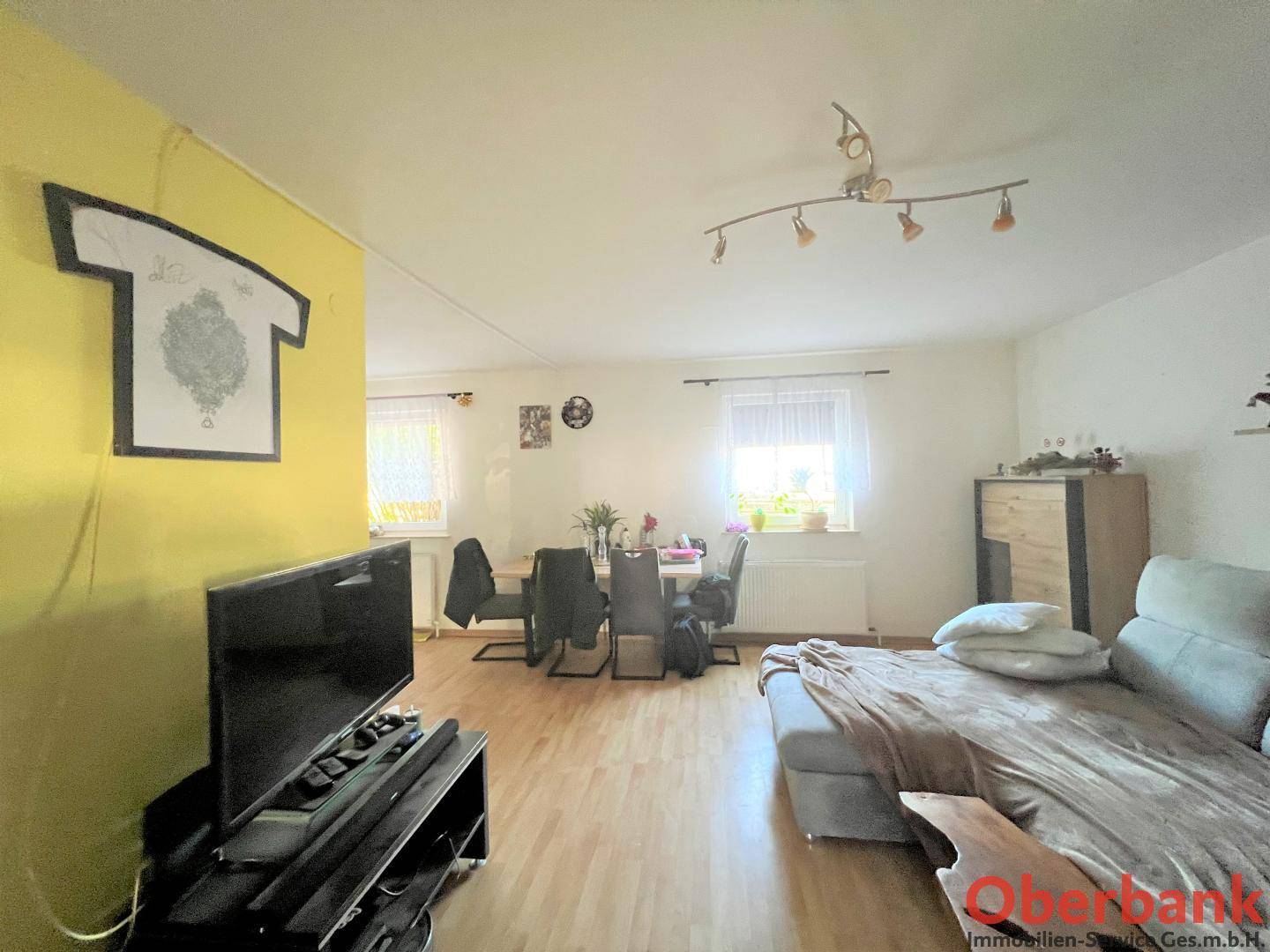 Heller Wohn- und Essbereich mit Laminatboden, gemütlichem Sofa und Esstisch am Fenster.