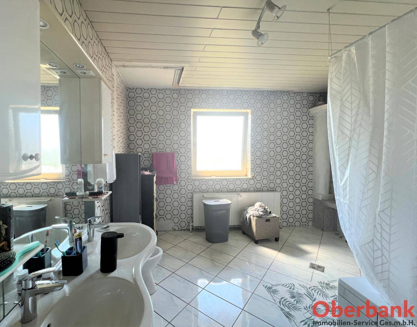 Geräumiges Badezimmer mit Fliesenboden, Doppelwaschbecken und Fenster für Tageslicht.