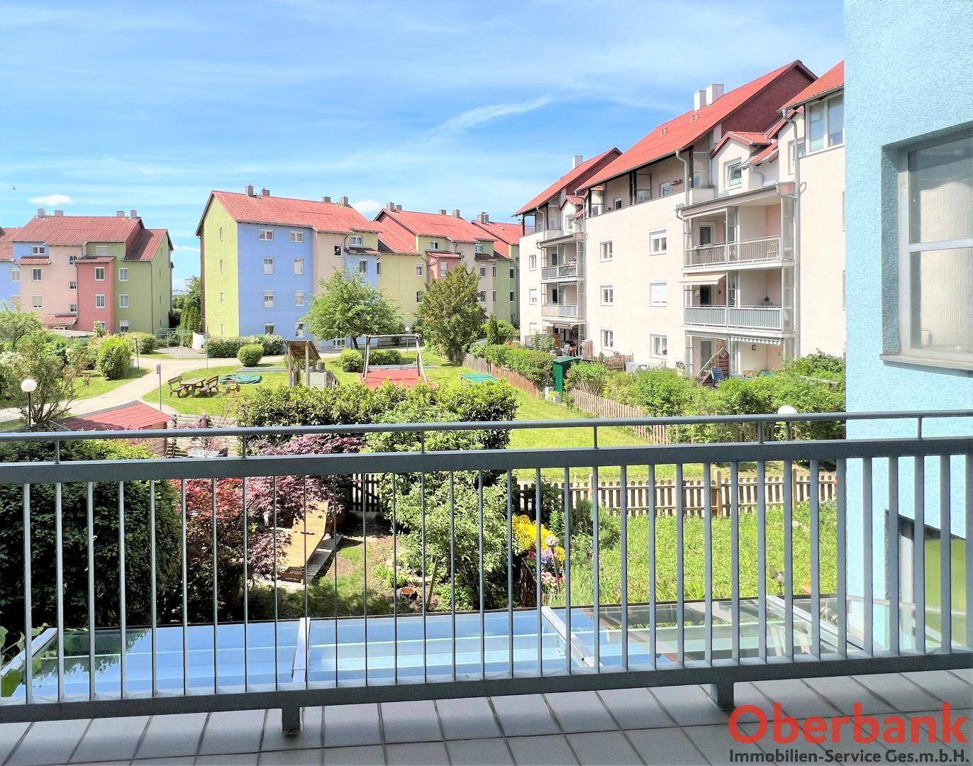 Weitläufiger Blick vom Balkon auf den grünen Innenhof und die benachbarten Wohngebäude.