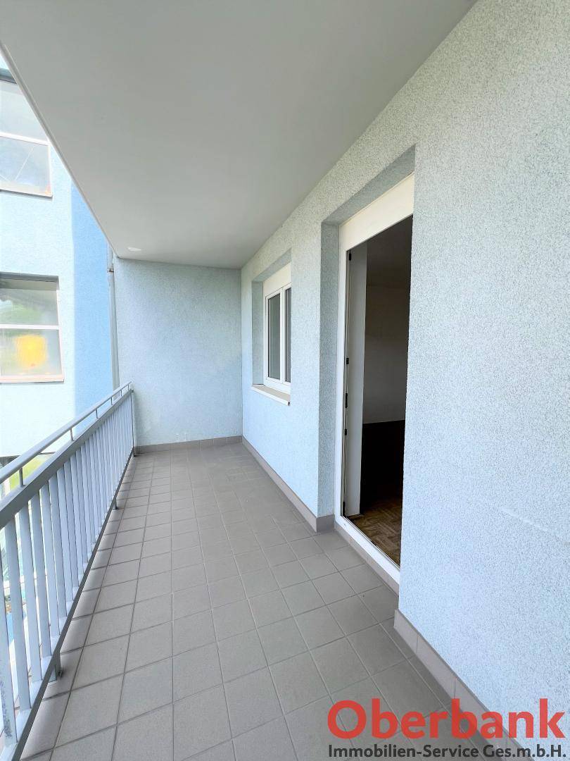Geräumiger Balkon mit hellblauen Wänden und Fliesenboden, bereit zur individuellen Gestaltung.