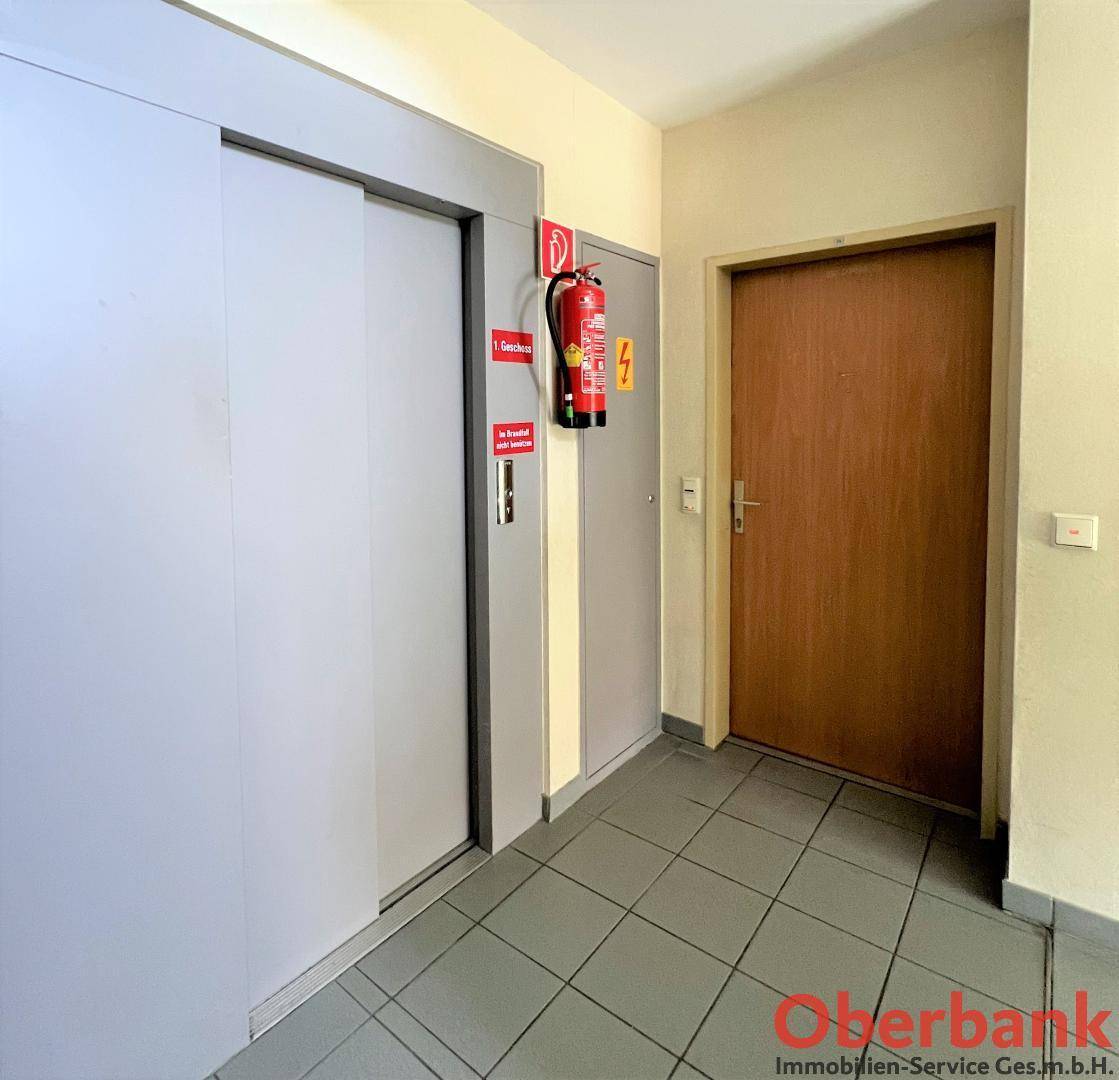 Heller Flur im Gebäude mit Zugang zum modernen Aufzug und Brandschutzvorrichtungen.