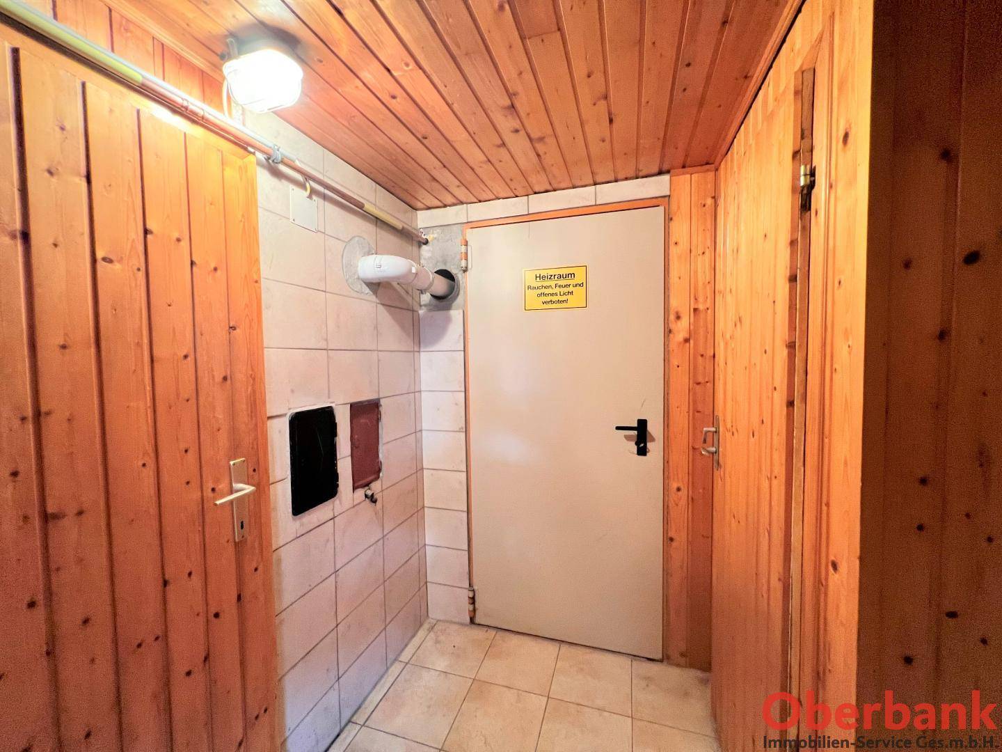 Heizraum mit Holzverkleidung an Decke und Wänden sowie gefliestem Boden im Kellerbereich.