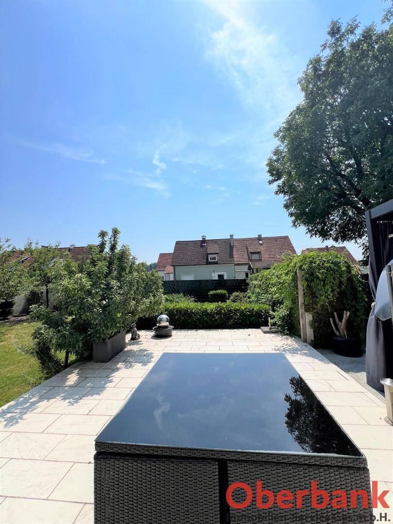 Große gepflasterte Terrasse mit Gartenmöbeln und Blick auf die umliegenden Häuser und den Garten.