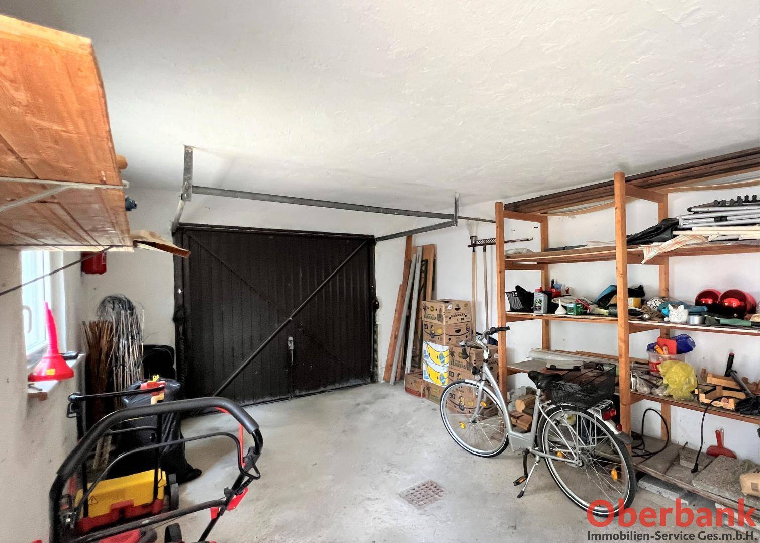 Geräumige Garage mit Lagerregalen, Fahrrädern und Gartengeräten, ideal für Stauraum.