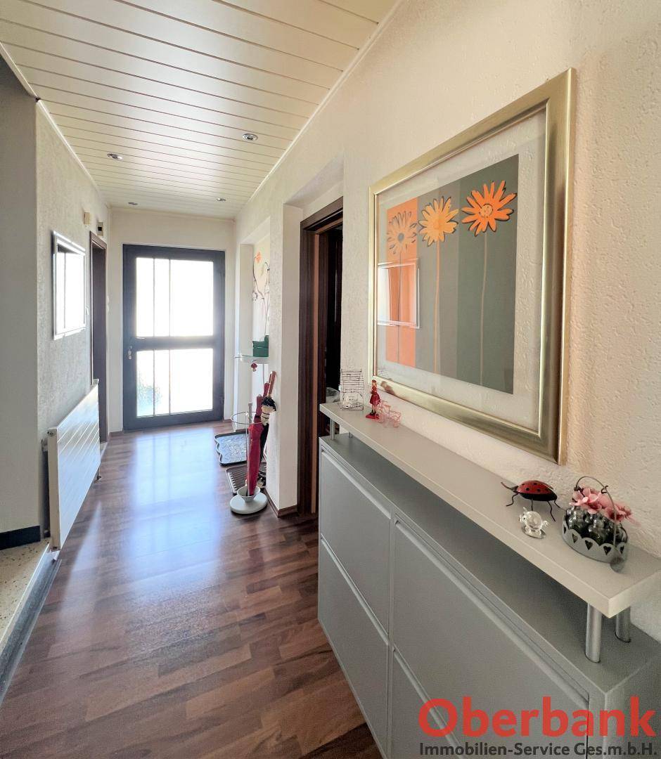 Eingangsbereich mit Holzboden, Schuhschrank und heller Beleuchtung.