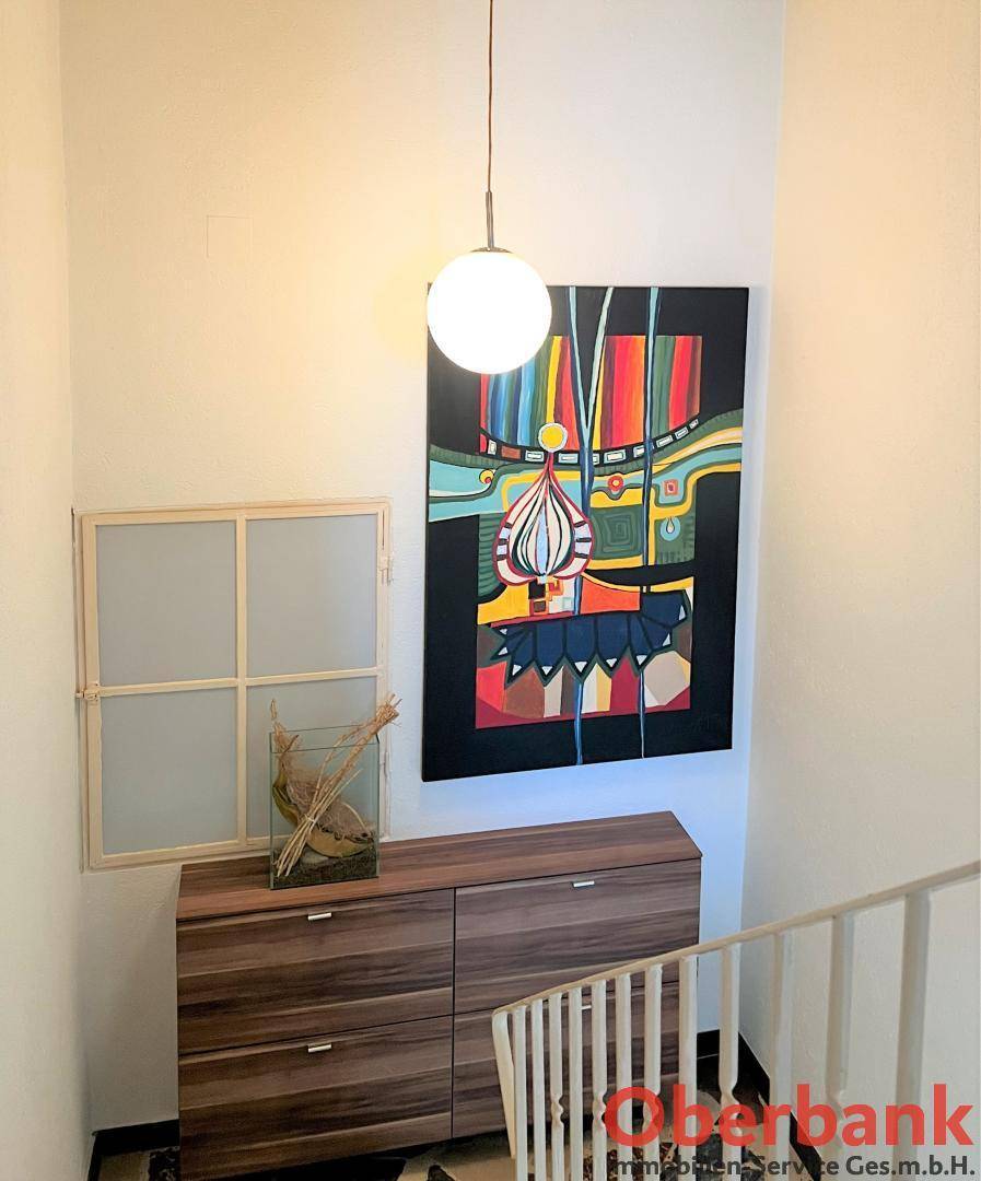Treppenabsatz mit Kommode und farbenfrohem abstrakten Kunstwerk.