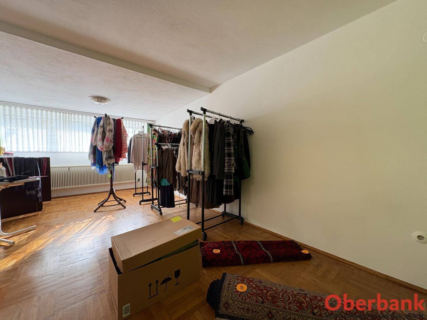 Großer Raum mit Kleiderständern und Fenstern, vielseitig nutzbar.