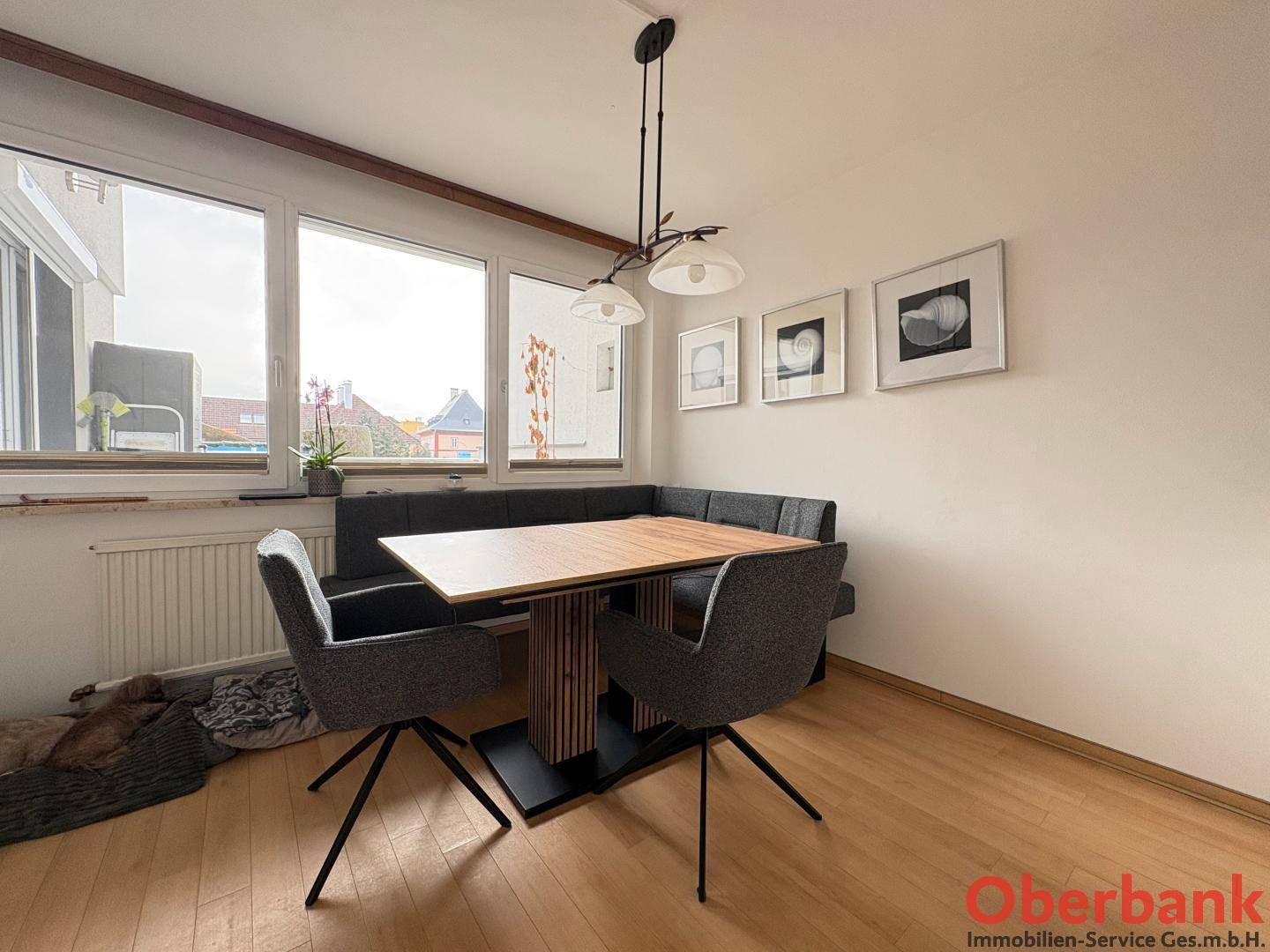Heller Essbereich mit moderner Eckbank, Esstisch und großen Fenstern.