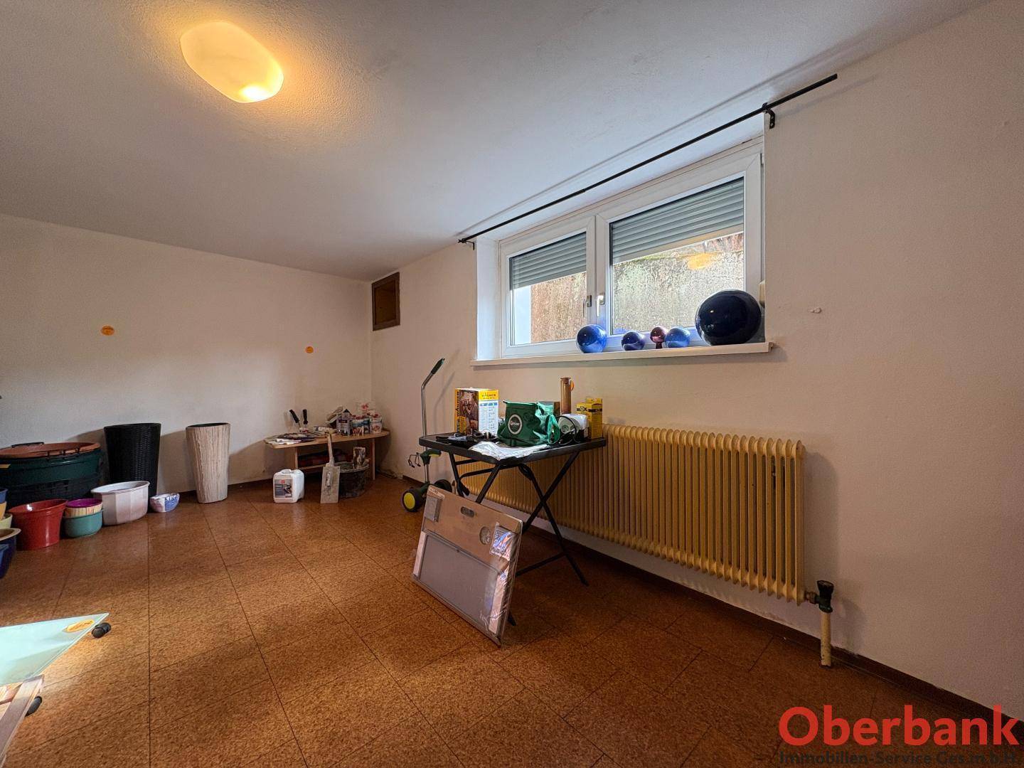 Kellerraum mit Fenster, Heizkörper und verschiedenen Gegenständen.