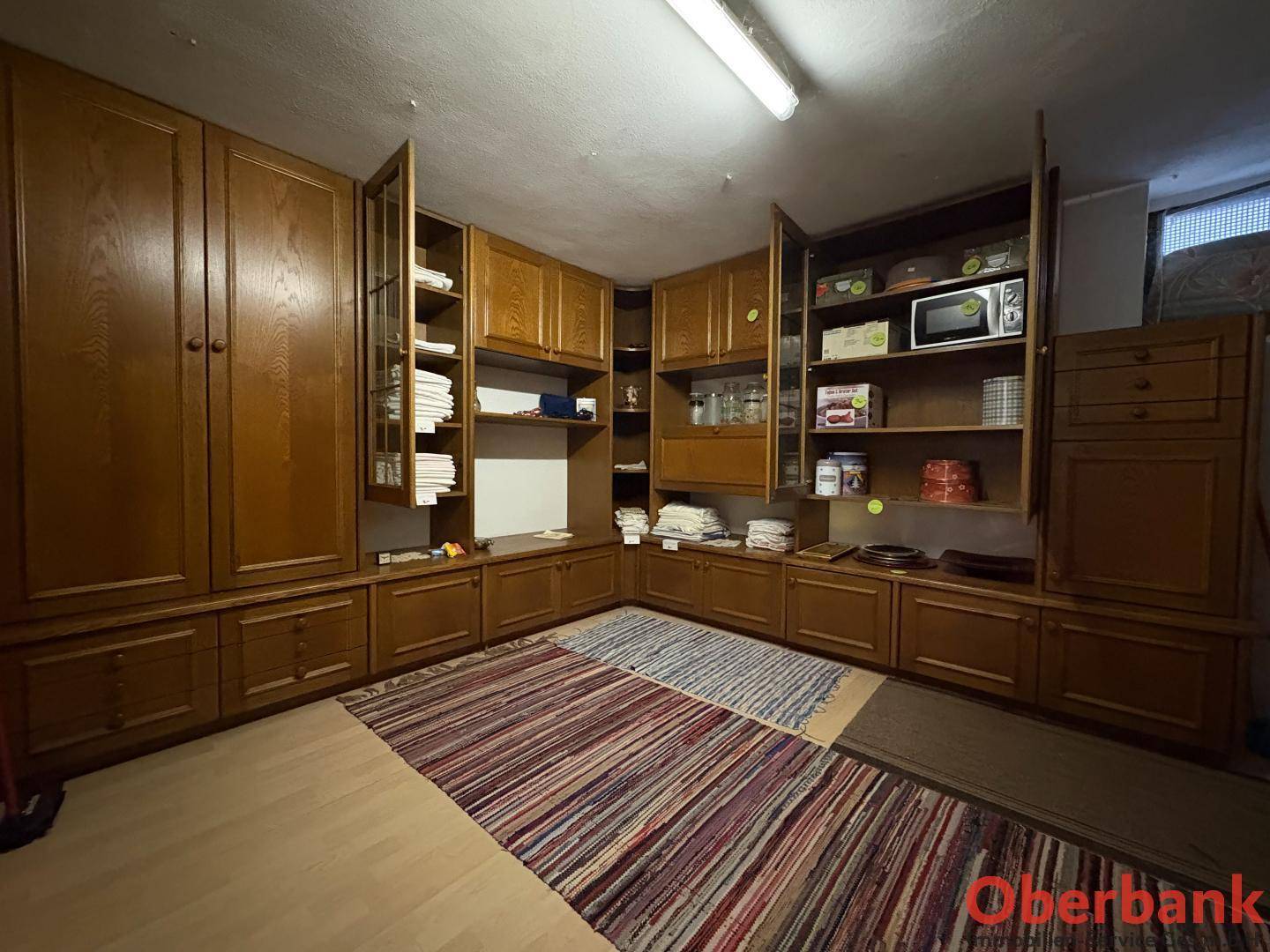 Großer Abstellraum mit vielen Holzschränken und Teppichen.