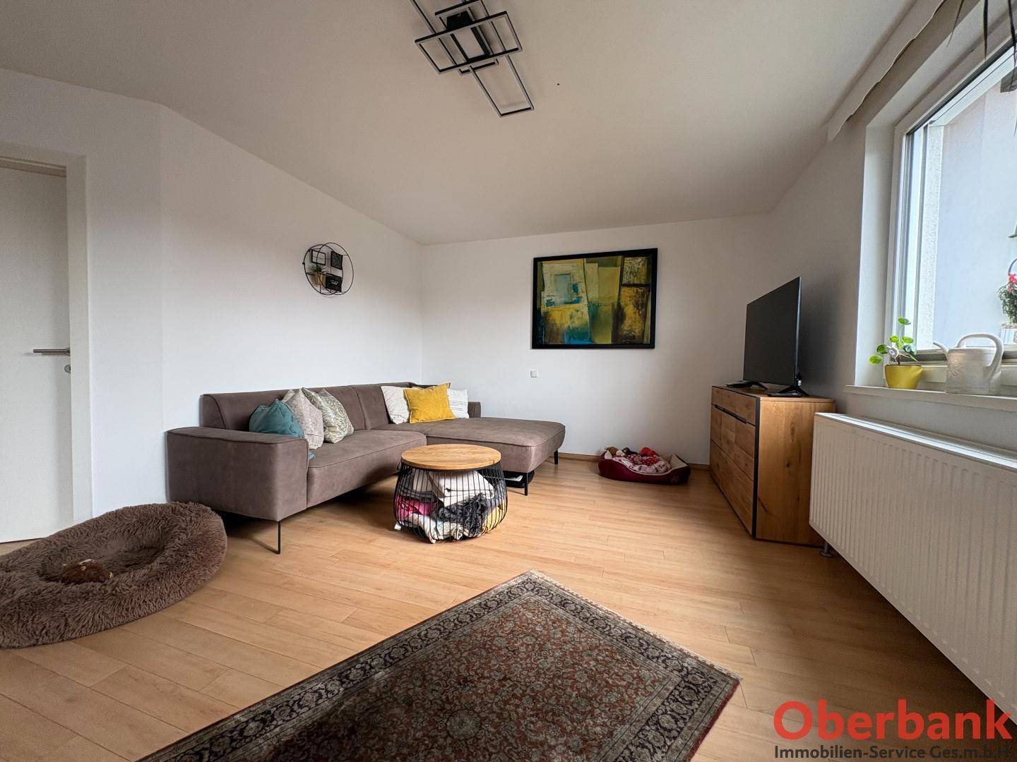 Gemütliches Wohnzimmer mit Ecksofa, Holzboden und moderner Dekoration.