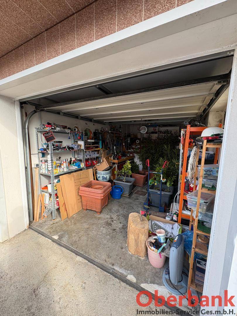 Geräumige Garage mit Lagerregalen und Platz für Gartengeräte.