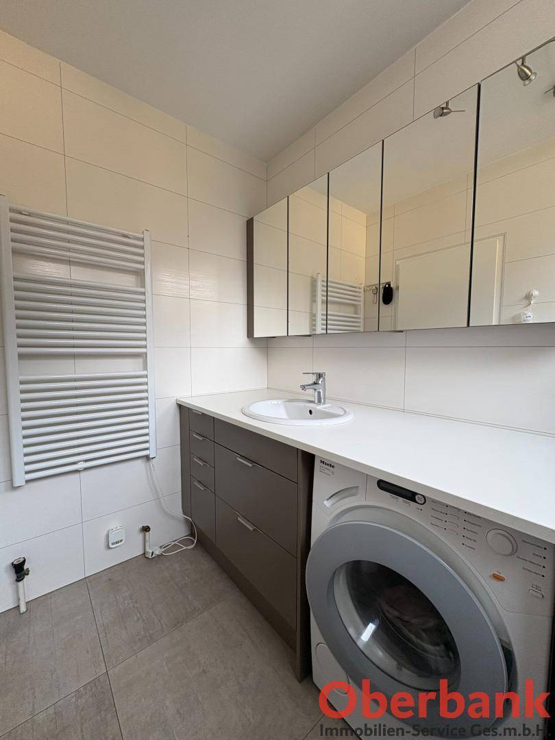 Modernes Badezimmer mit Waschmaschine, Einzelwaschbecken und Spiegelschrank.