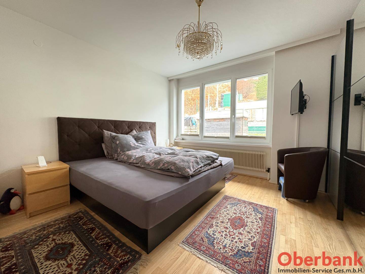 Helles Schlafzimmer mit Doppelbett, Holzboden und großem Fenster.