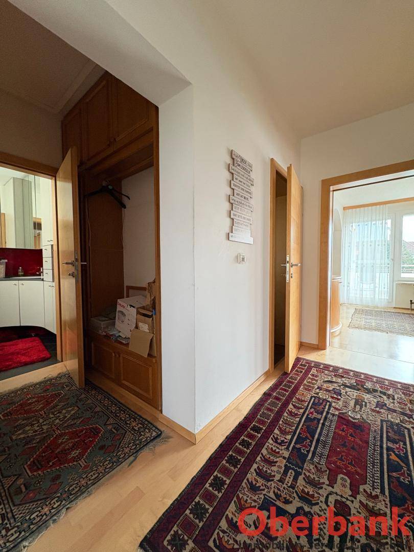 Heller Flur mit Holzboden, integriertem Einbauschrank und traditionellen Teppichen.