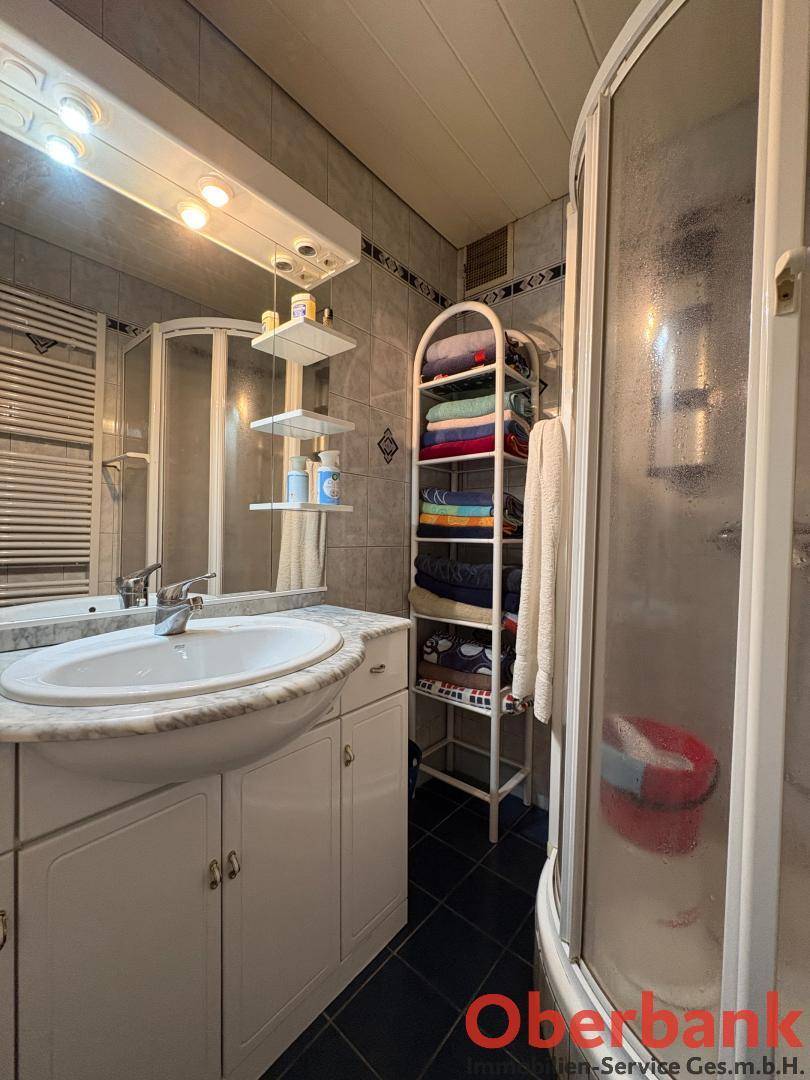 Badezimmer mit Duschkabine, Einzelwaschbecken und Spiegelschrank.