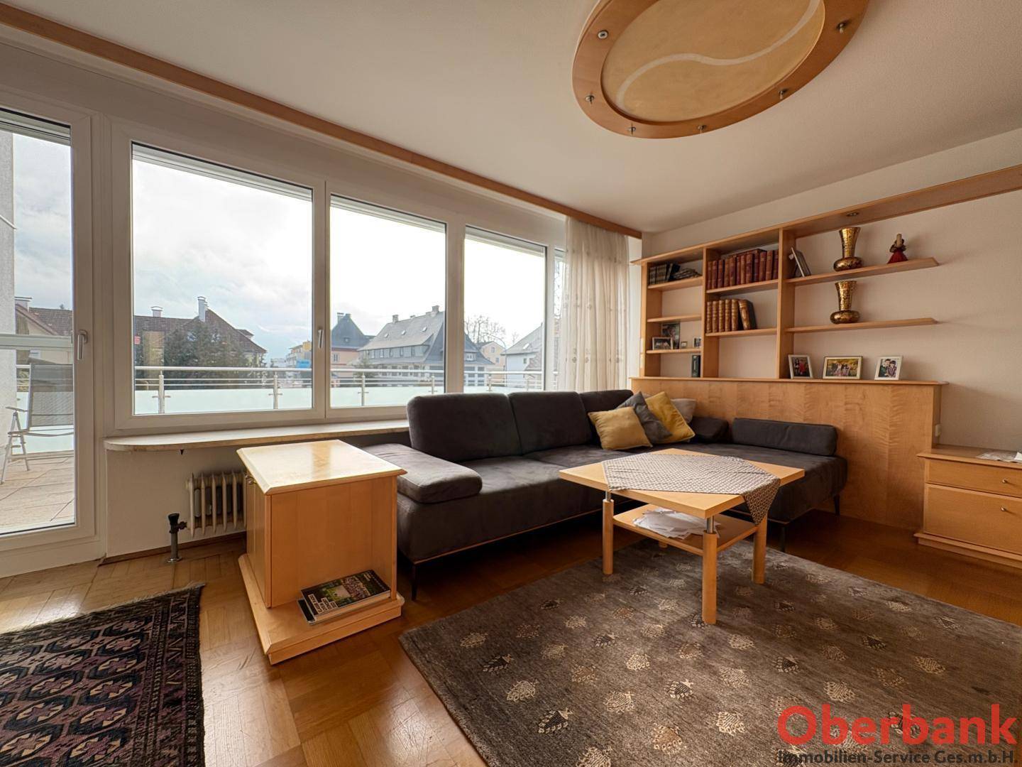Helles Wohnzimmer mit Holzboden, Sofa und großem Fenster mit Terrassenzugang.